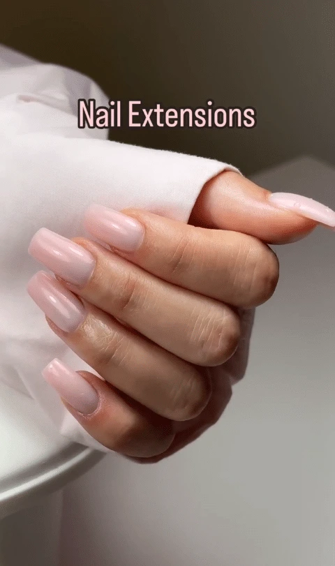 Hand with light pink square nail extensions.