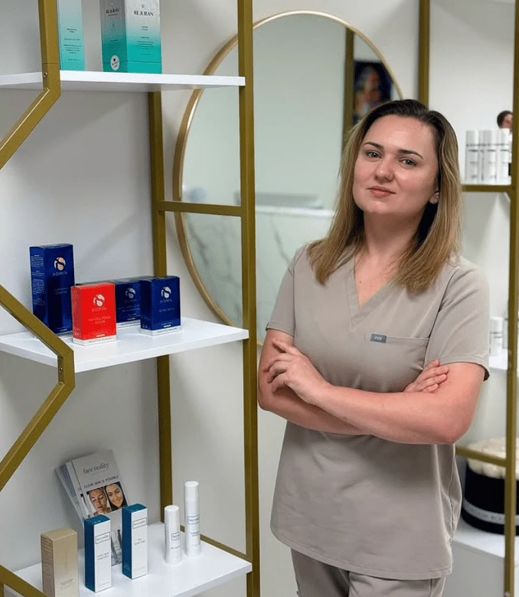 Woman in tan scrubs with arms crossed in a med spa.