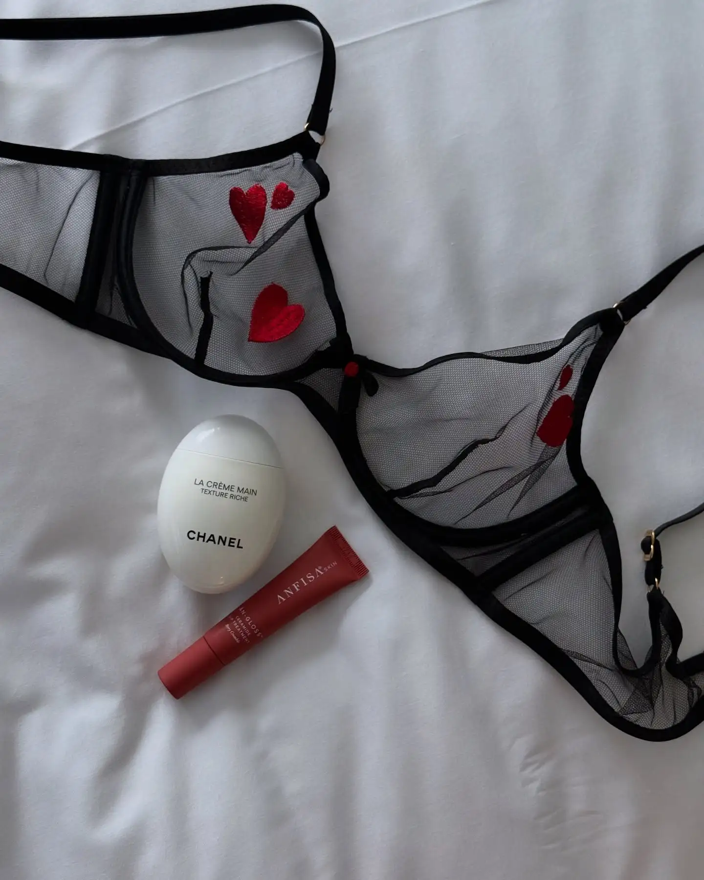 Black mesh bra with red hearts, Chanel hand cream, and lip gloss.