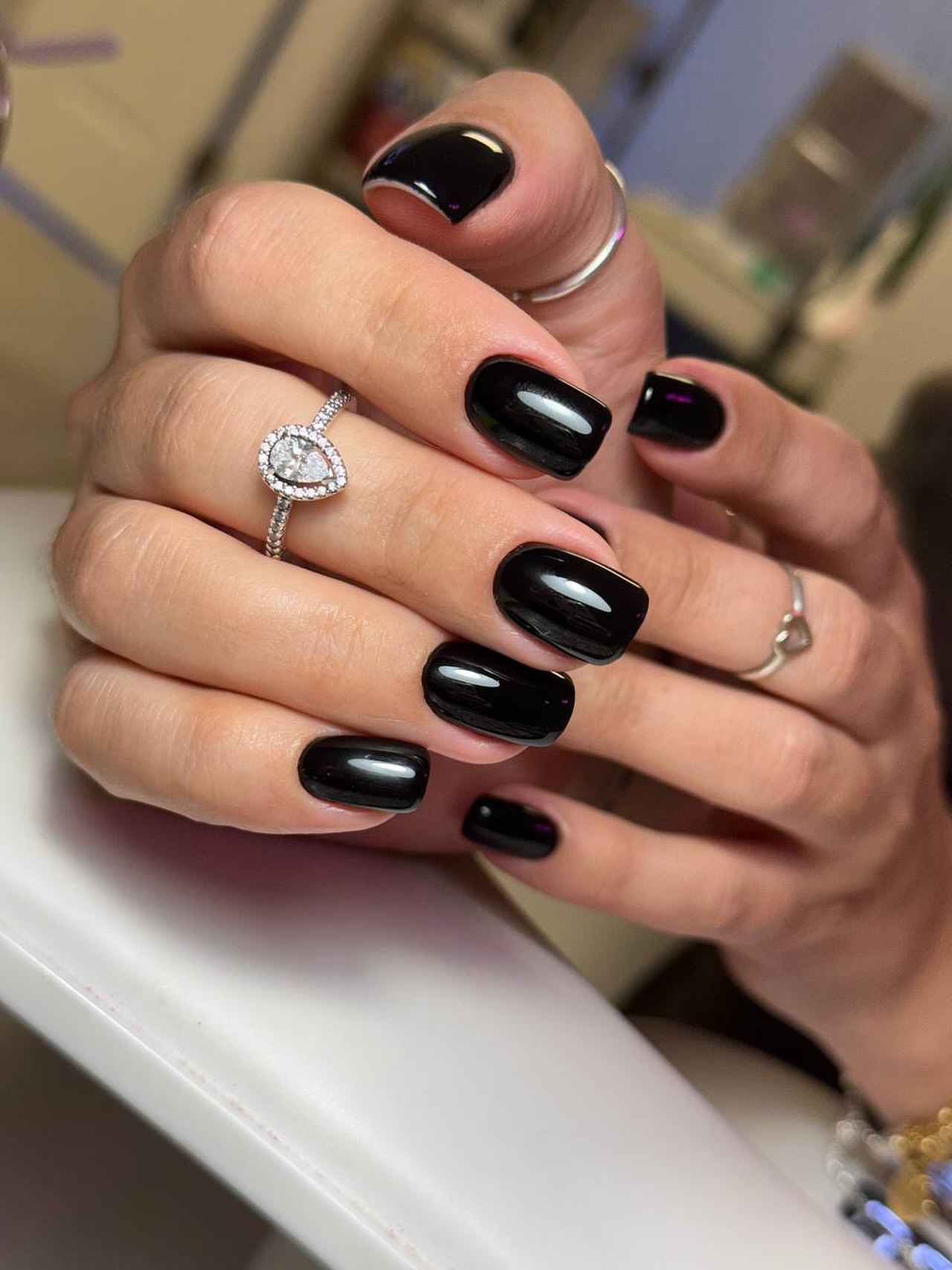 Hands with glossy black nails and diamond rings.