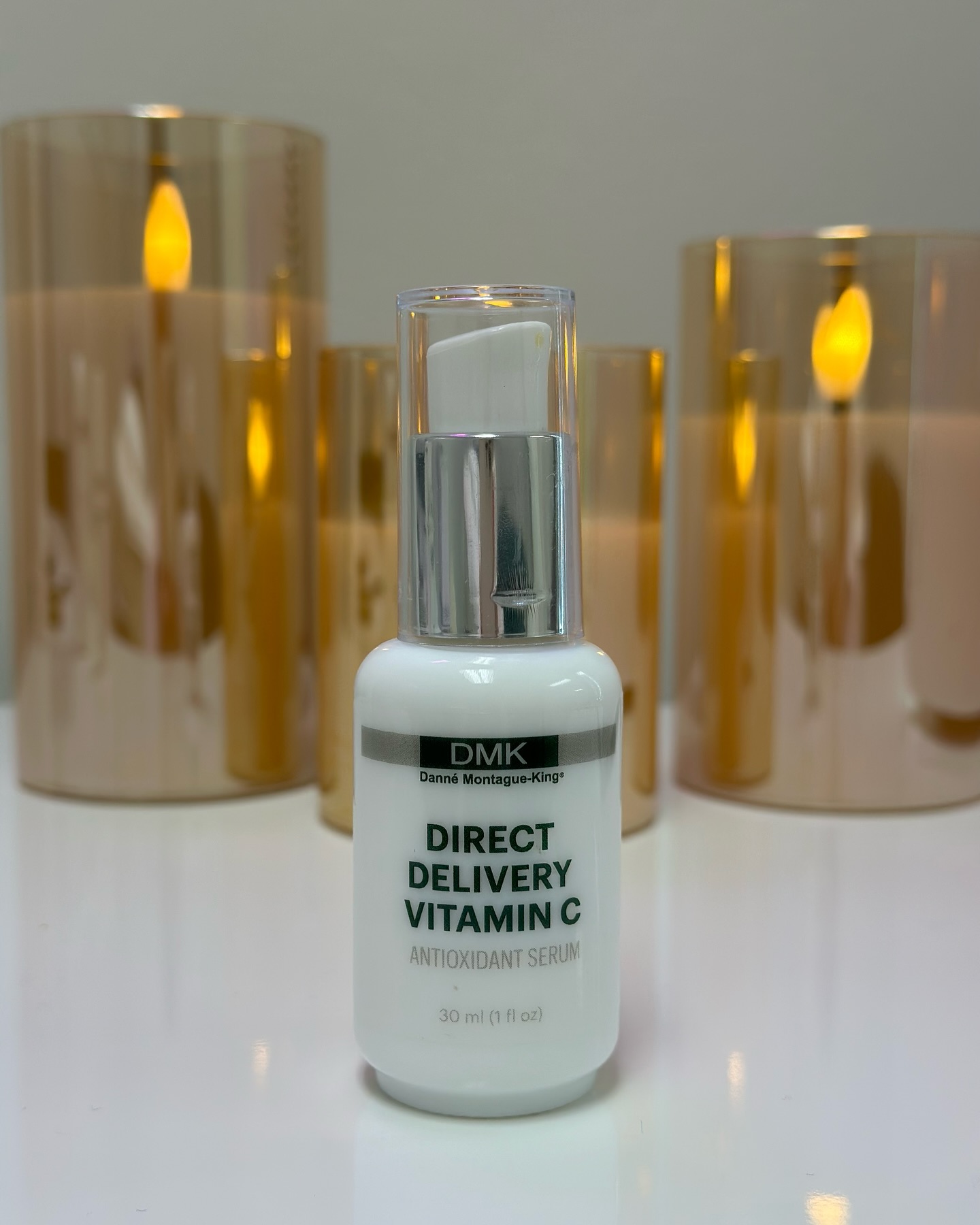 nn DMK Direct Delivery Vitamin C antioxidant serum bottle with candles.