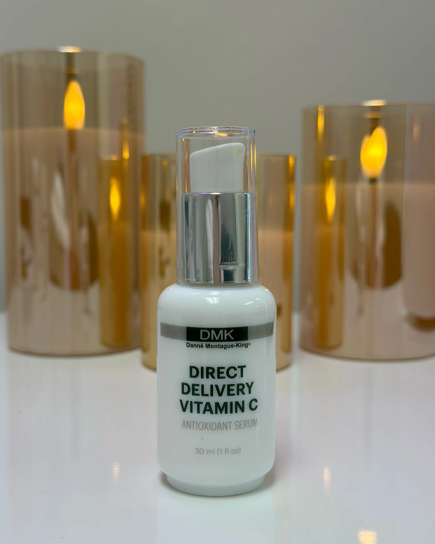 nn DMK Direct Delivery Vitamin C antioxidant serum bottle with candles.