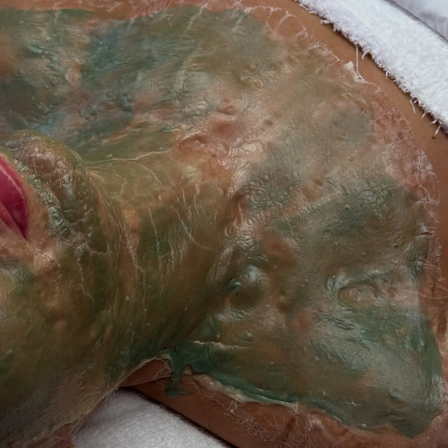 Close up of a face with a green mask applied at Skin Lounge Med Spa.