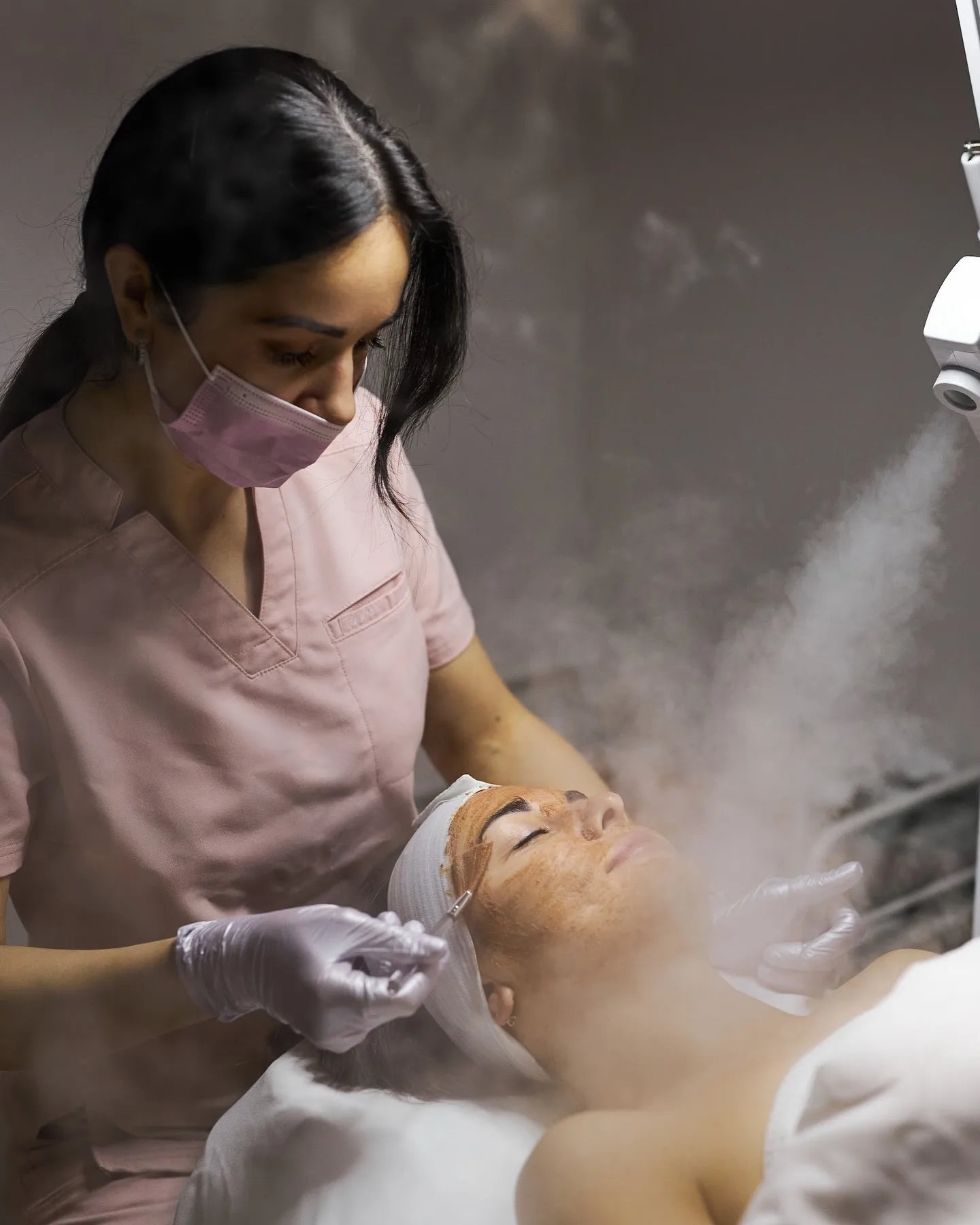 Esthetician applies facial treatment with steam at a med spa.