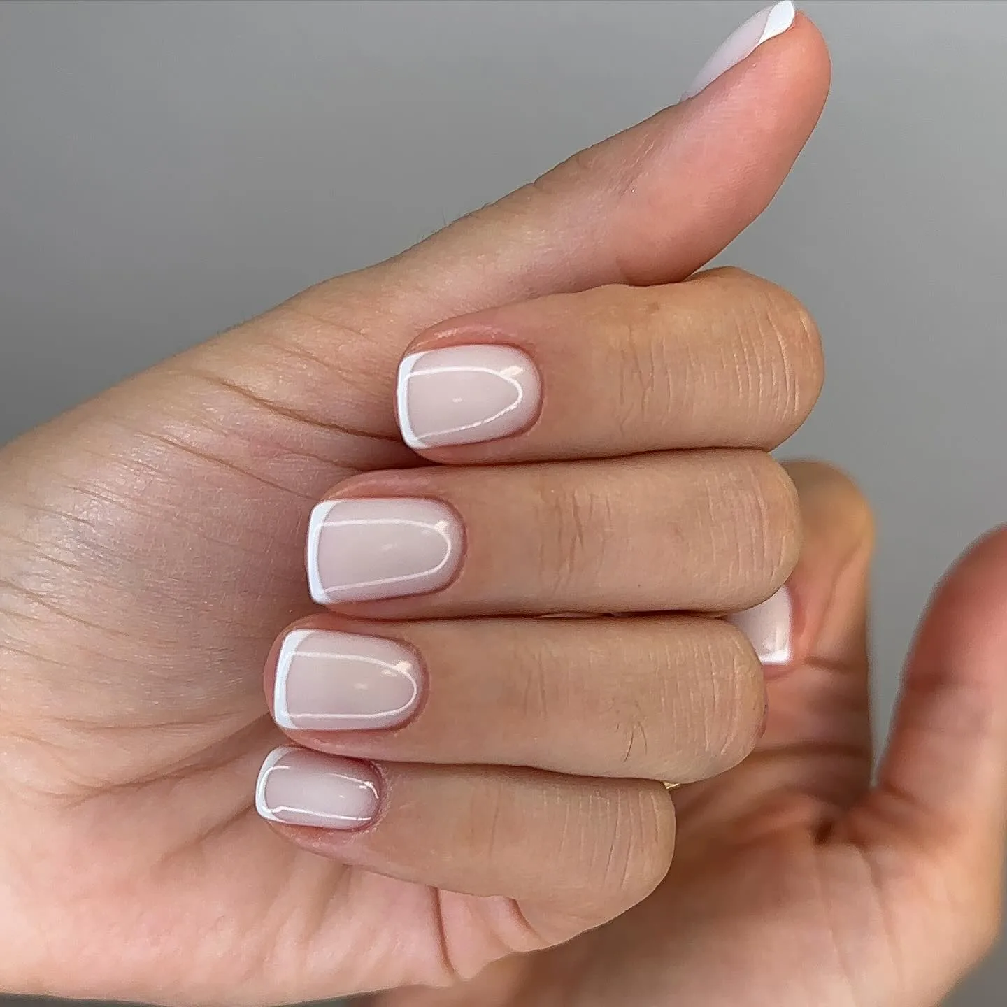 Close-up of a hand with a French manicure at Skin Lounge Med Spa.