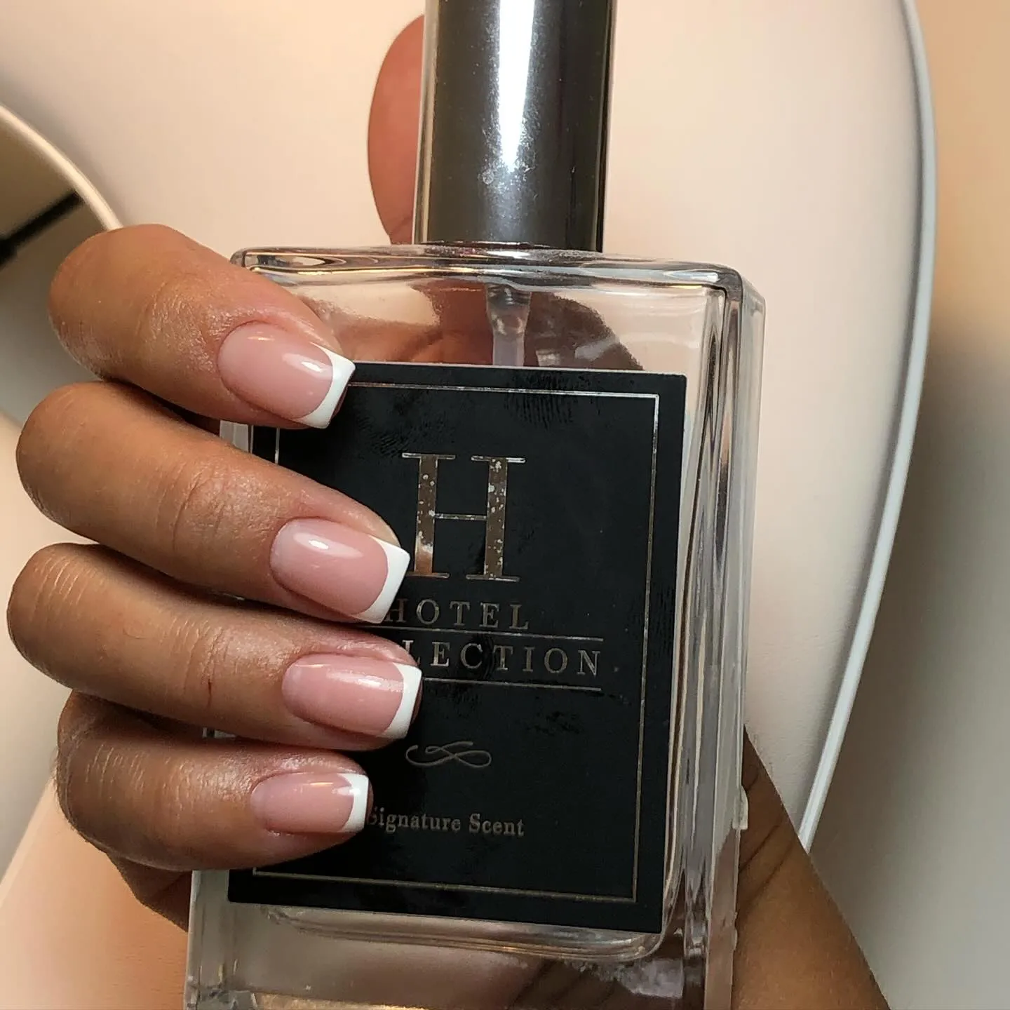 nn Hand with French manicure holding a bottle labeled "HOTEL COLLECTION Signature Scent".