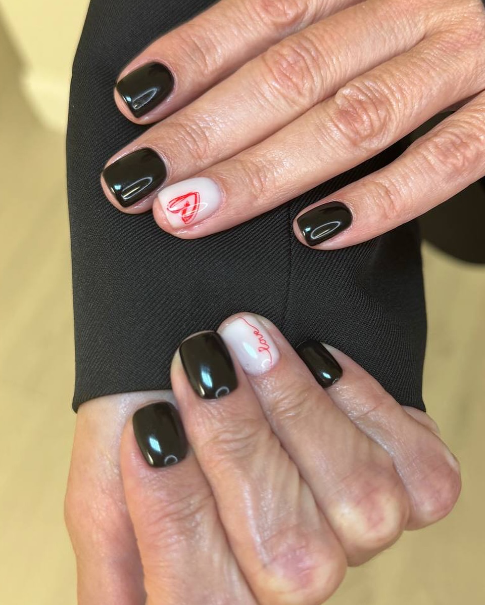 Dark nails with red heart and "love" designs.