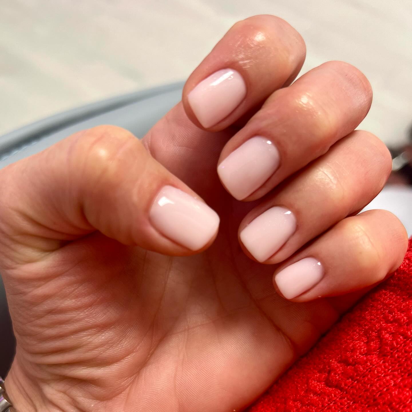 Light pink, short, square-shaped nails on a hand.