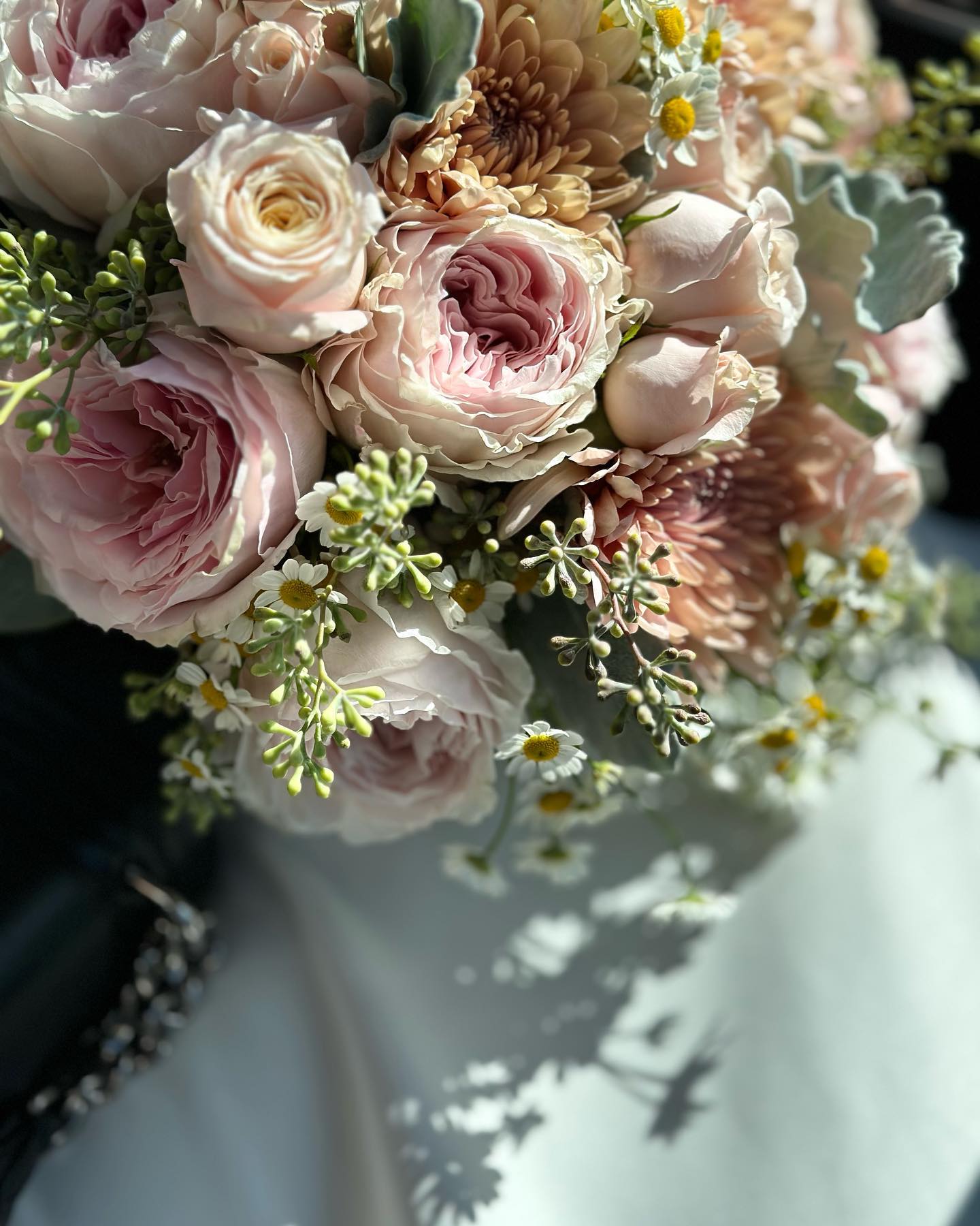 nn Soft pink roses and small white flowers in a bouquet.