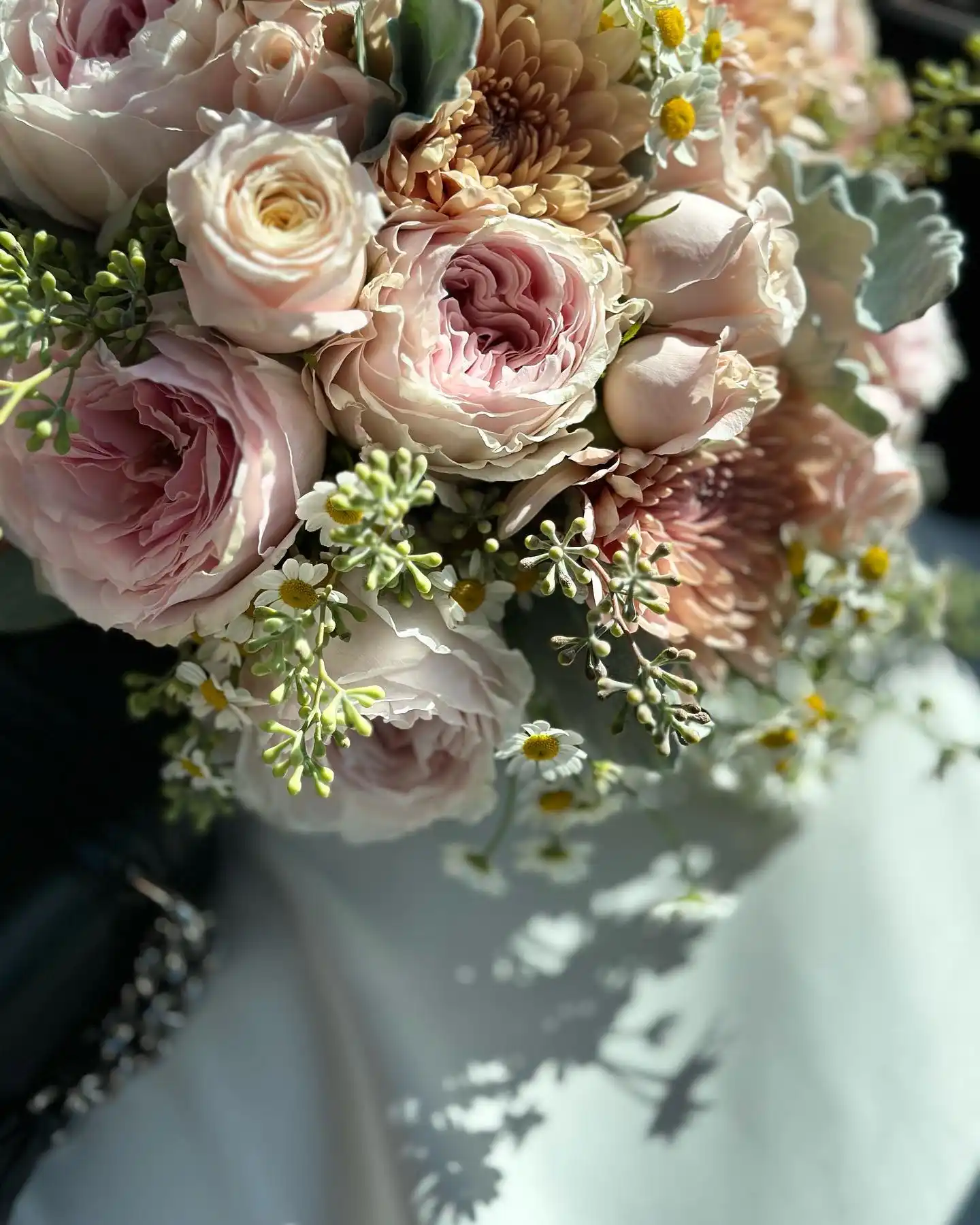 nn Soft pink roses and small white flowers in a bouquet.