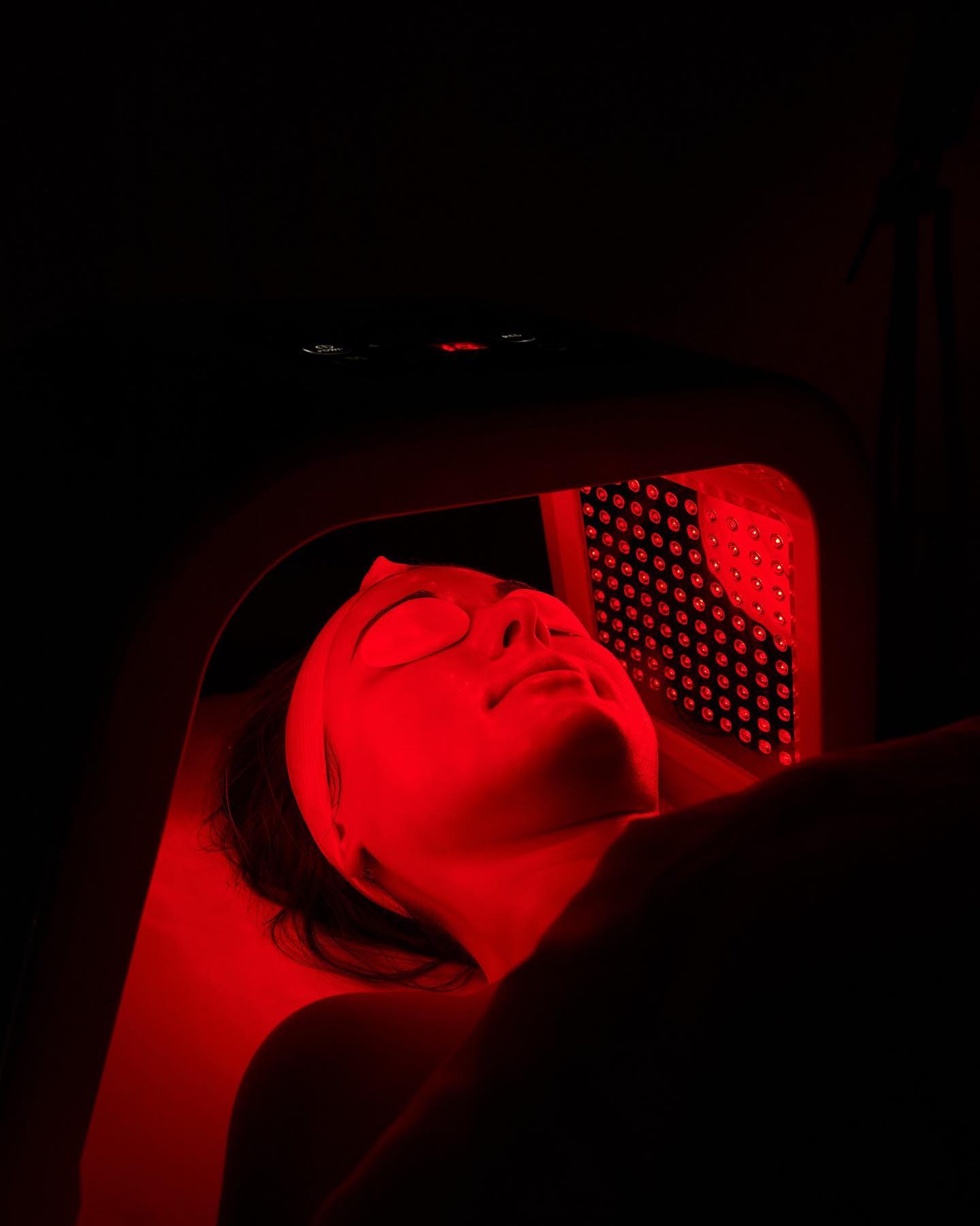 Face illuminated by red LED light therapy at Skin Lounge Med Spa.