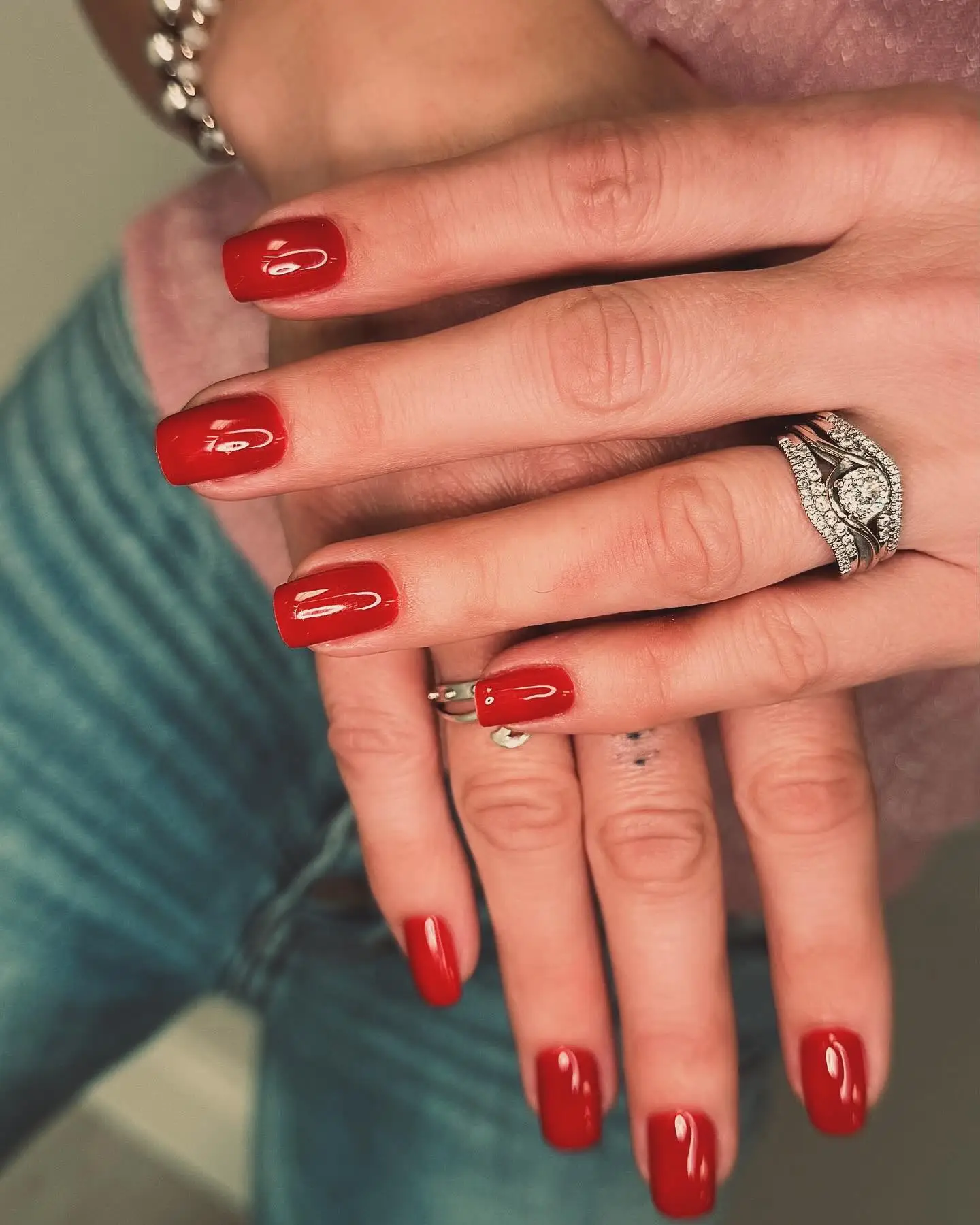Hands with red nails and diamond rings at Skin Lounge Med Spa.