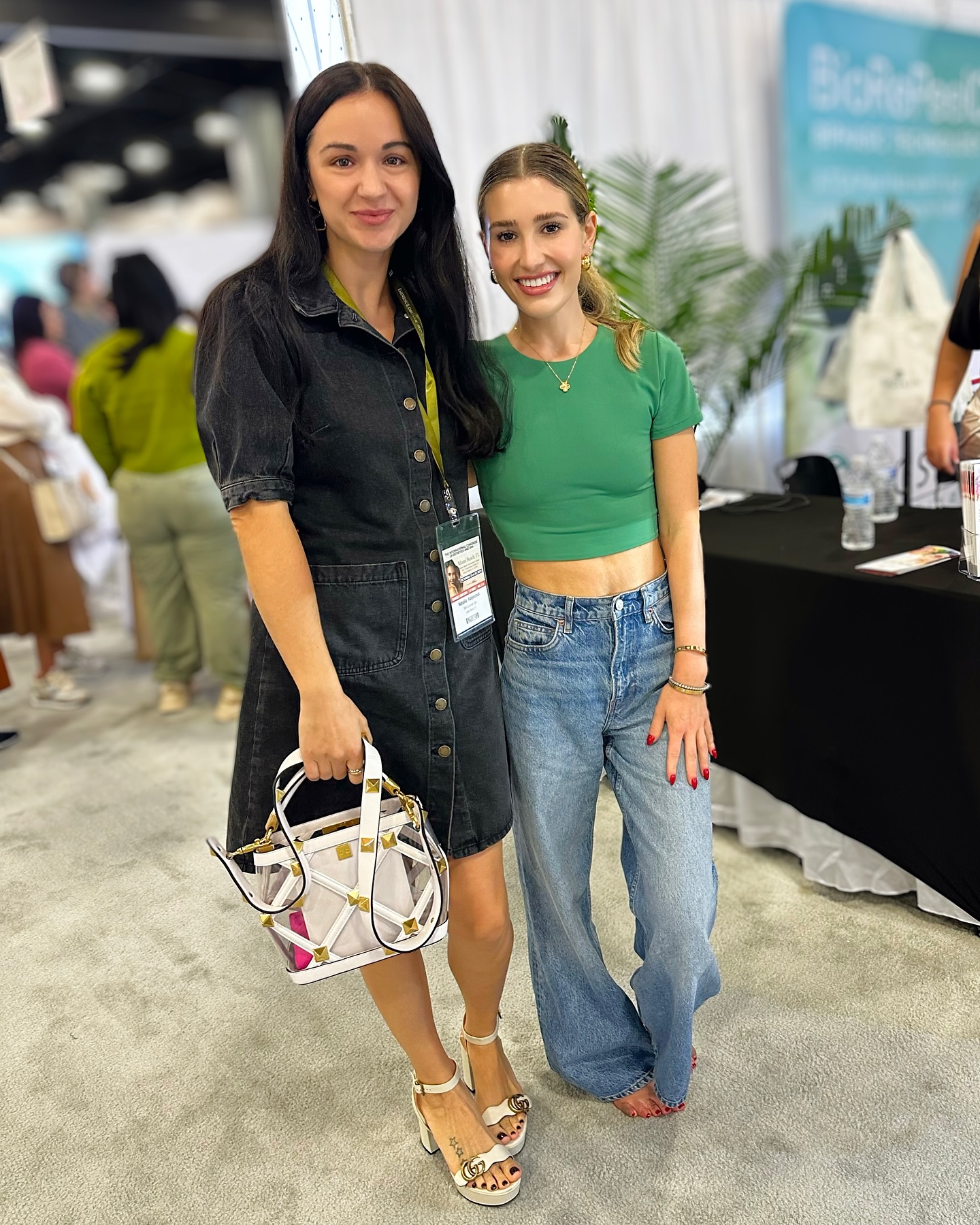 Two women posing at an event with a sign that says "SkinPro".