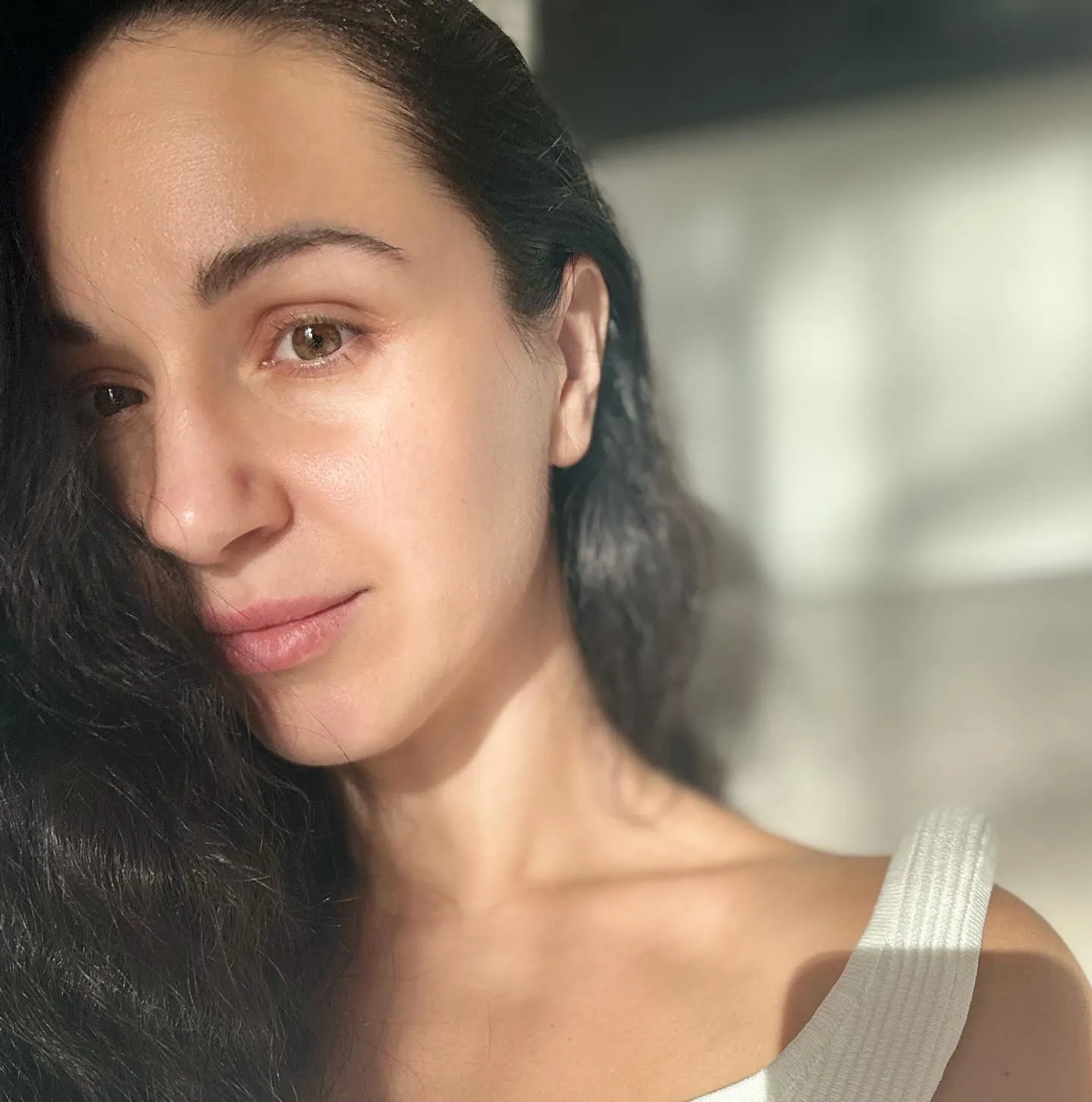 Woman with dark hair and brown eyes, bathed in sunlight.