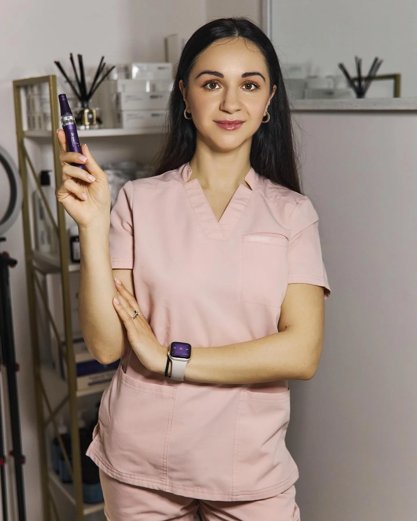 Woman in pink scrubs holds a purple pen device.